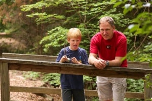 a boy and his man standing on a bridge